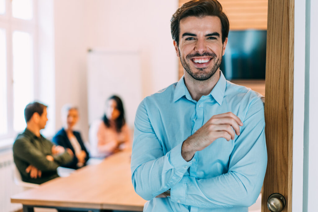 Shot of a young financial professional smiling while standing in front of his team in the office.