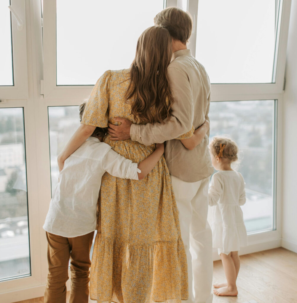 family of four hugging while looking out window