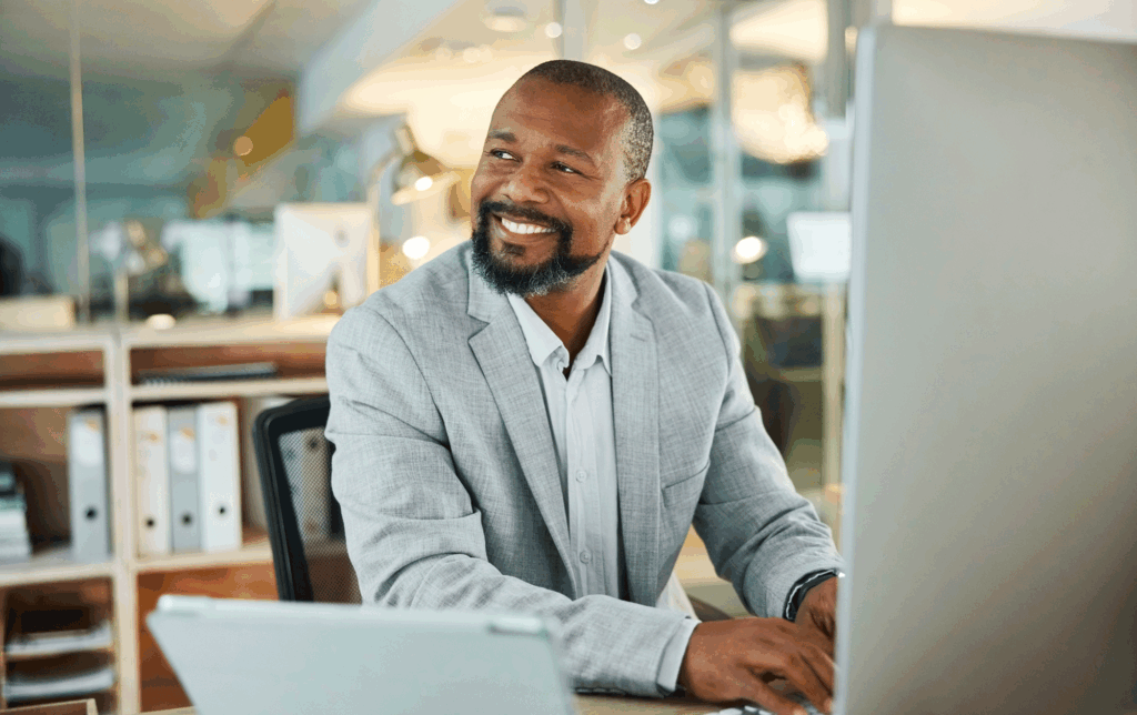 African American man in suit jacket smiling at computer.