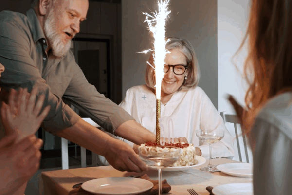 family celebrating grandparent birthday party with sparkling candles