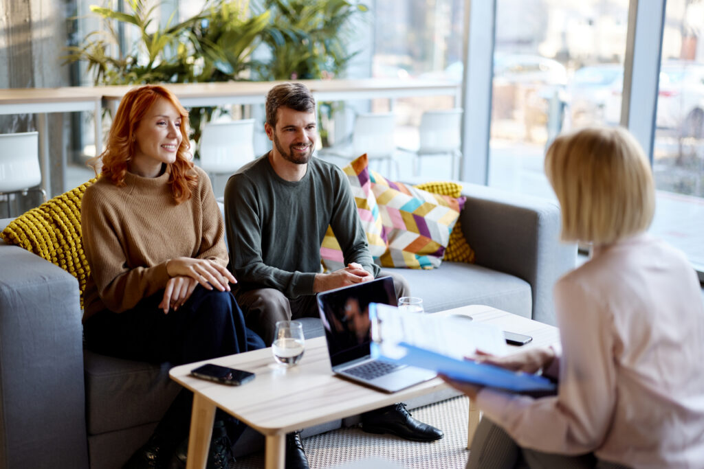 Happy couple talking about future plans with their financial advisor during a meeting at casual office.