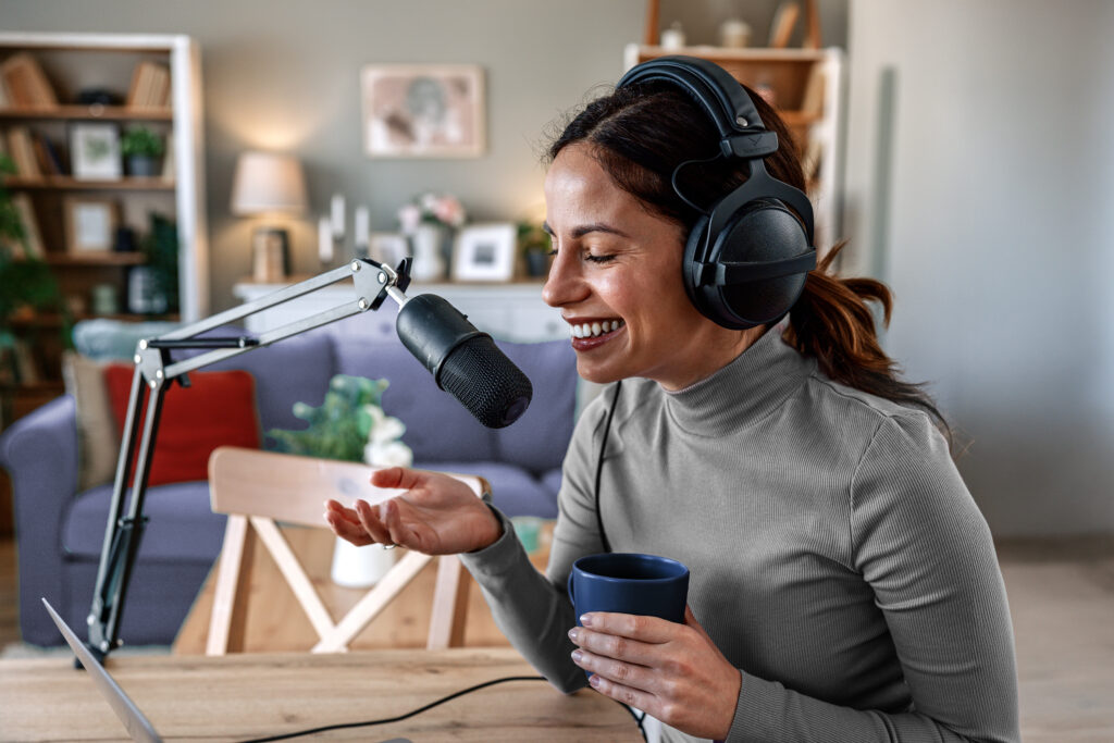 Woman smiling while wearing her headphones and recording a podcast in her home