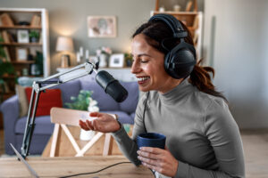 Woman smiling while wearing her headphones and recording a podcast in her home