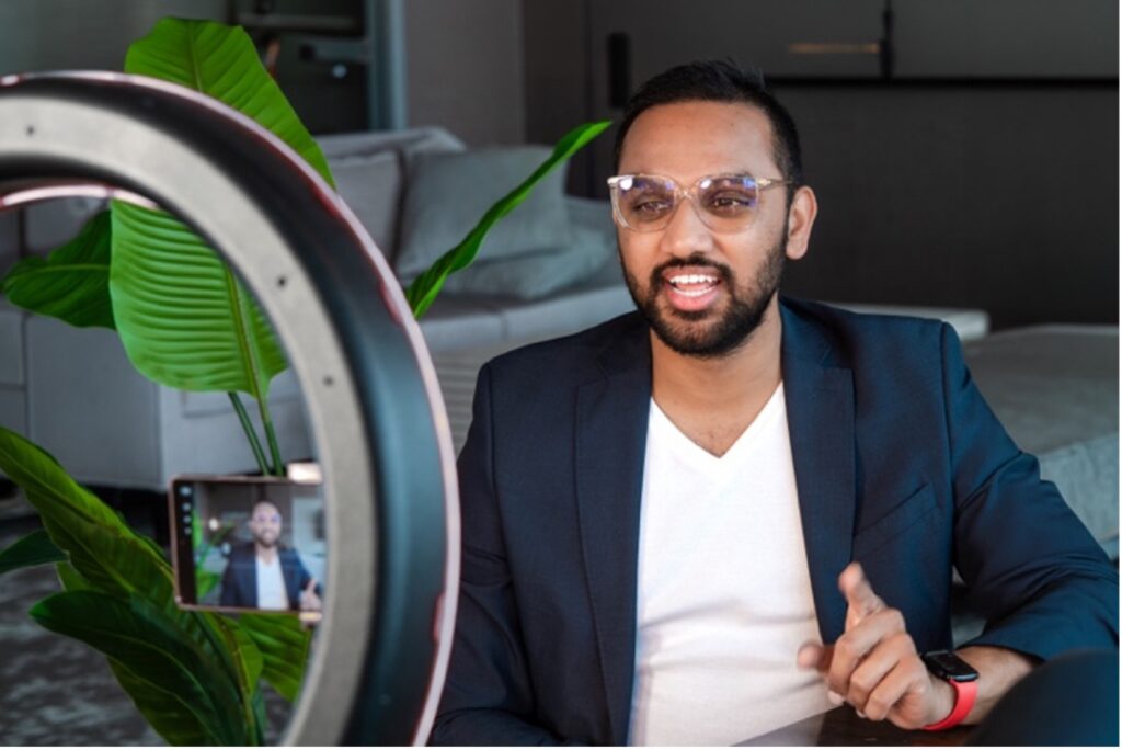 Modern male influencer in suit jacket recording video with phone camera for clients